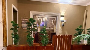 A reception area with a wooden gate, potted plants, and a wall with a welcome sign. - Appartement Rustique (Yaoundé)