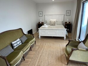 Ein Schlafzimmer mit einem großen Bett, zwei Nachttischen, einem grünen Sofa und einem Sessel.