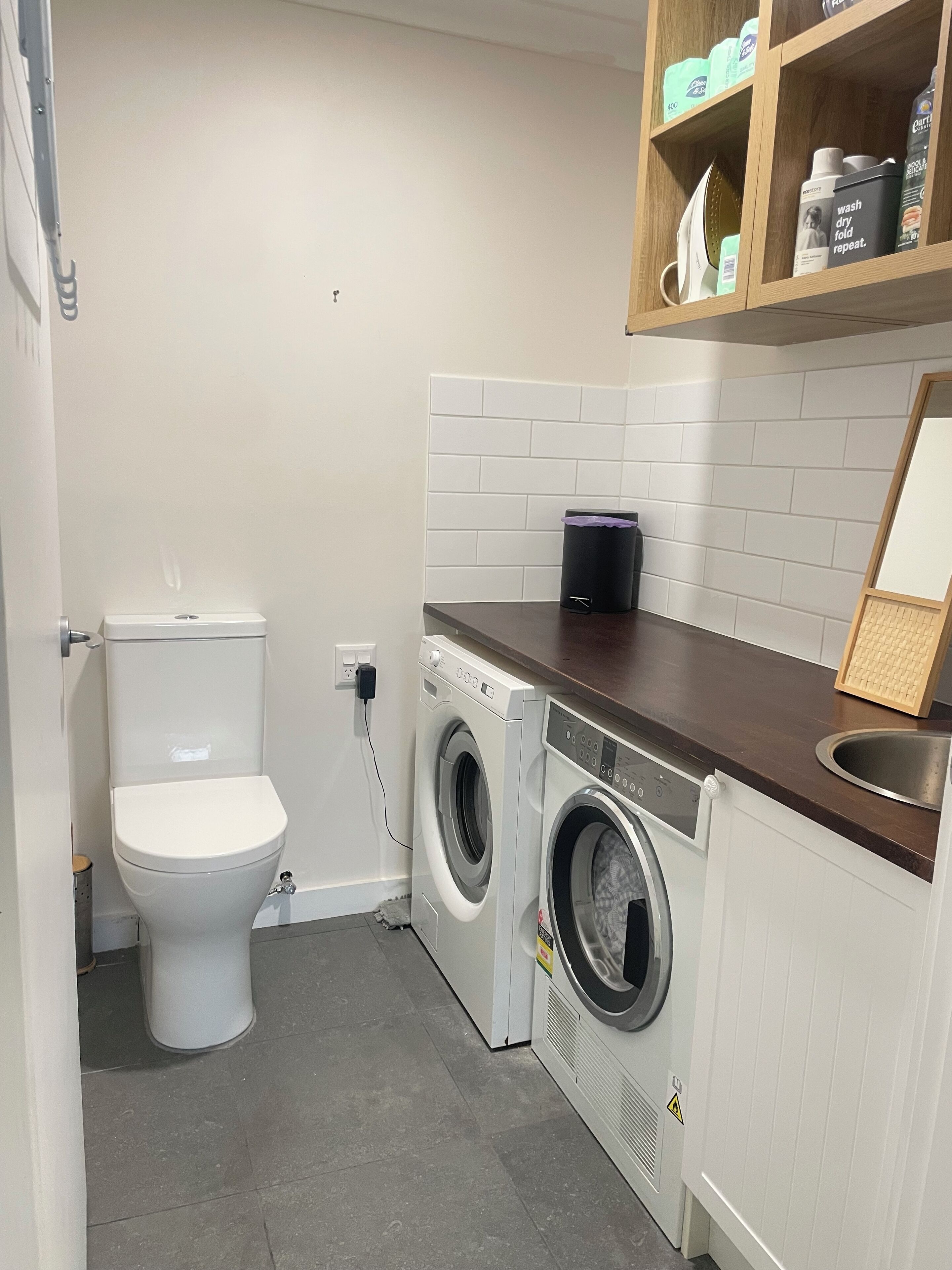 Une petite buanderie équipée d’un lave-linge, d’un sèche-linge et de toilettes.