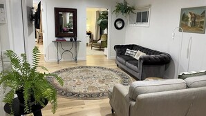 Una sala de estar con un sofá, una mesa de centro, un tapete y una planta en maceta.