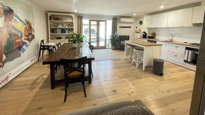 Una cocina amplia con suelo de madera, una isla central y armarios blancos.