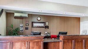 A reception desk with a clock, framed certificates, and a plant. - Super 8 by Wyndham Mesa Downtown Near Convention Center (Mesa)