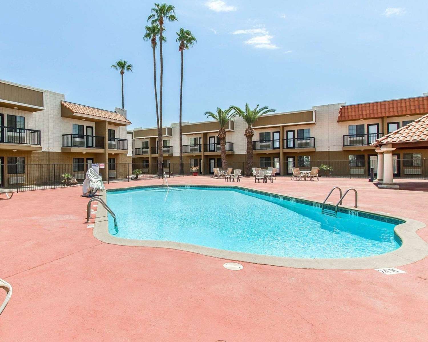 A pool area with a rectangular pool, lounge chairs, and palm trees.