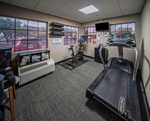 Un gimnasio con cinta de correr, bicicleta estática y dispensador de agua.