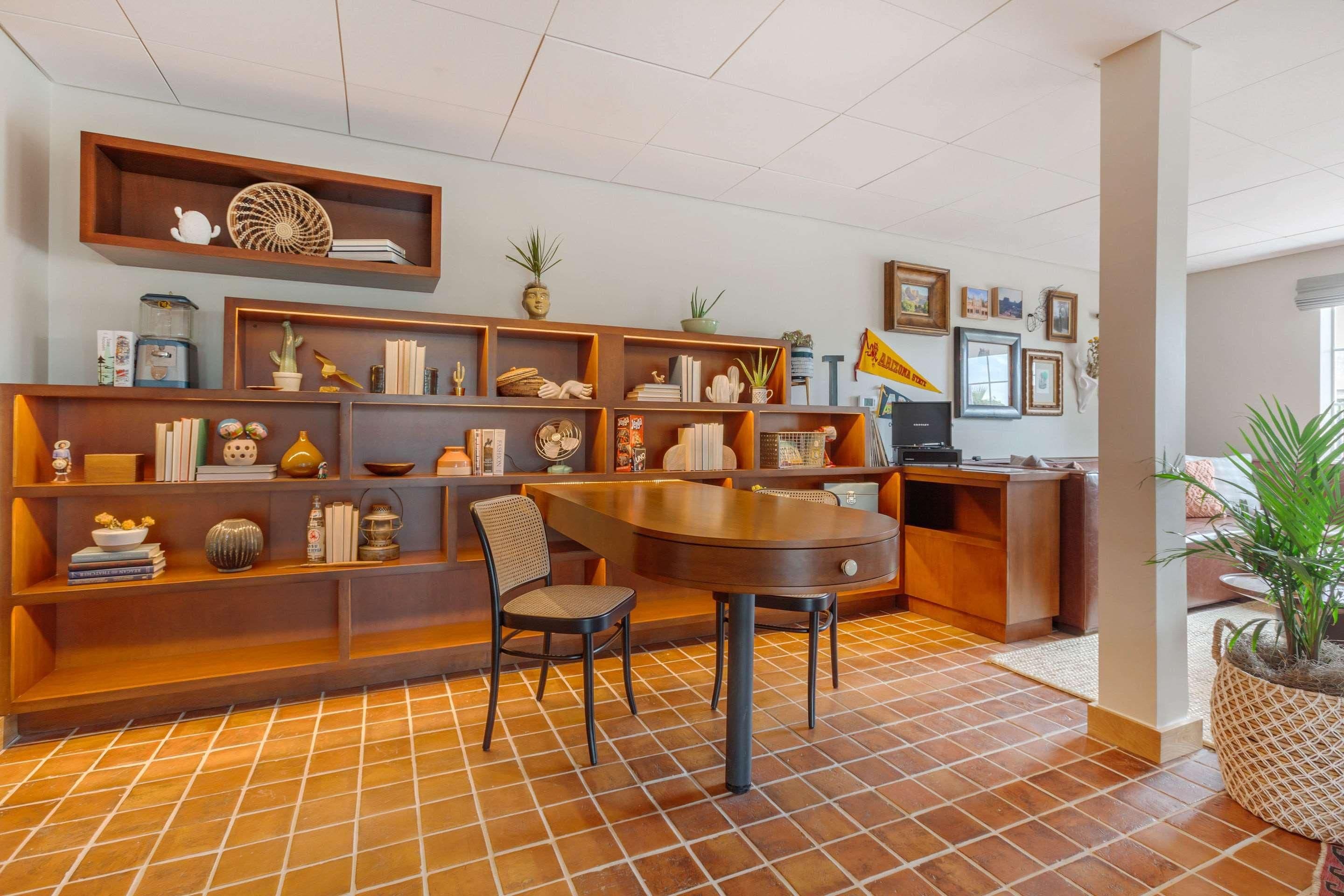 A room with a dining table, chairs, a bookshelf, and a potted plant.