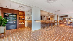 Un hall d’entrée spacieux avec un sol carrelé, un coin bar avec des tabourets et un réfrigérateur rempli de boissons.
