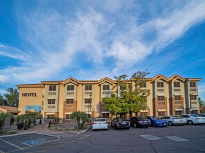 A hotel with a row of parked cars in front, a clear sky, and a sign indicating a handicapped parking space. - La Quinta Inn & Suites Tempe University / Phoenix (Tempe)
