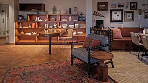 Un salon moderne avec une bibliothèque en bois, une table basse ronde et un tapis à motifs.