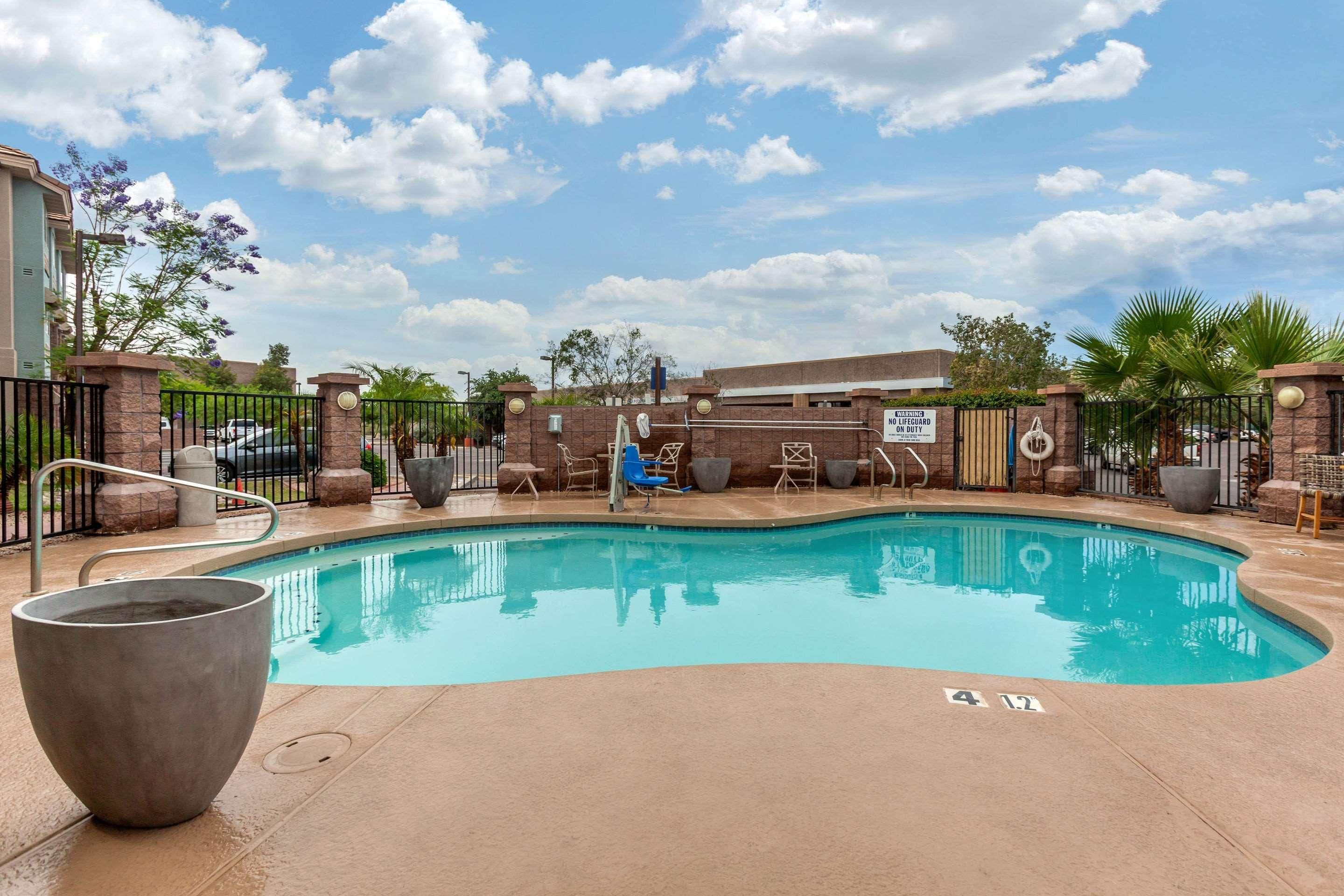 A swimming pool with a lounge area, a large planter, and a gate with a sign.