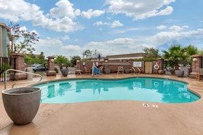 A swimming pool with a lounge area, a large planter, and a gate with a sign. - La Quinta Inn & Suites Tempe University / Phoenix (Tempe)