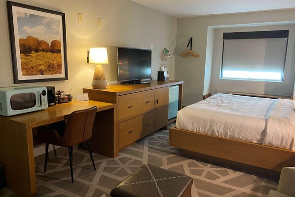 A hotel room with a bed, desk, chair, television, microwave, and a framed picture on the wall. - La Quinta Inn & Suites Tempe University / Phoenix (Tempe)