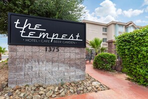 A sign for 'The Tempest Hotel, Cafe, Beer Garden' with a stone base and a clear sky in the background. - La Quinta Inn & Suites Tempe University / Phoenix (Tempe)