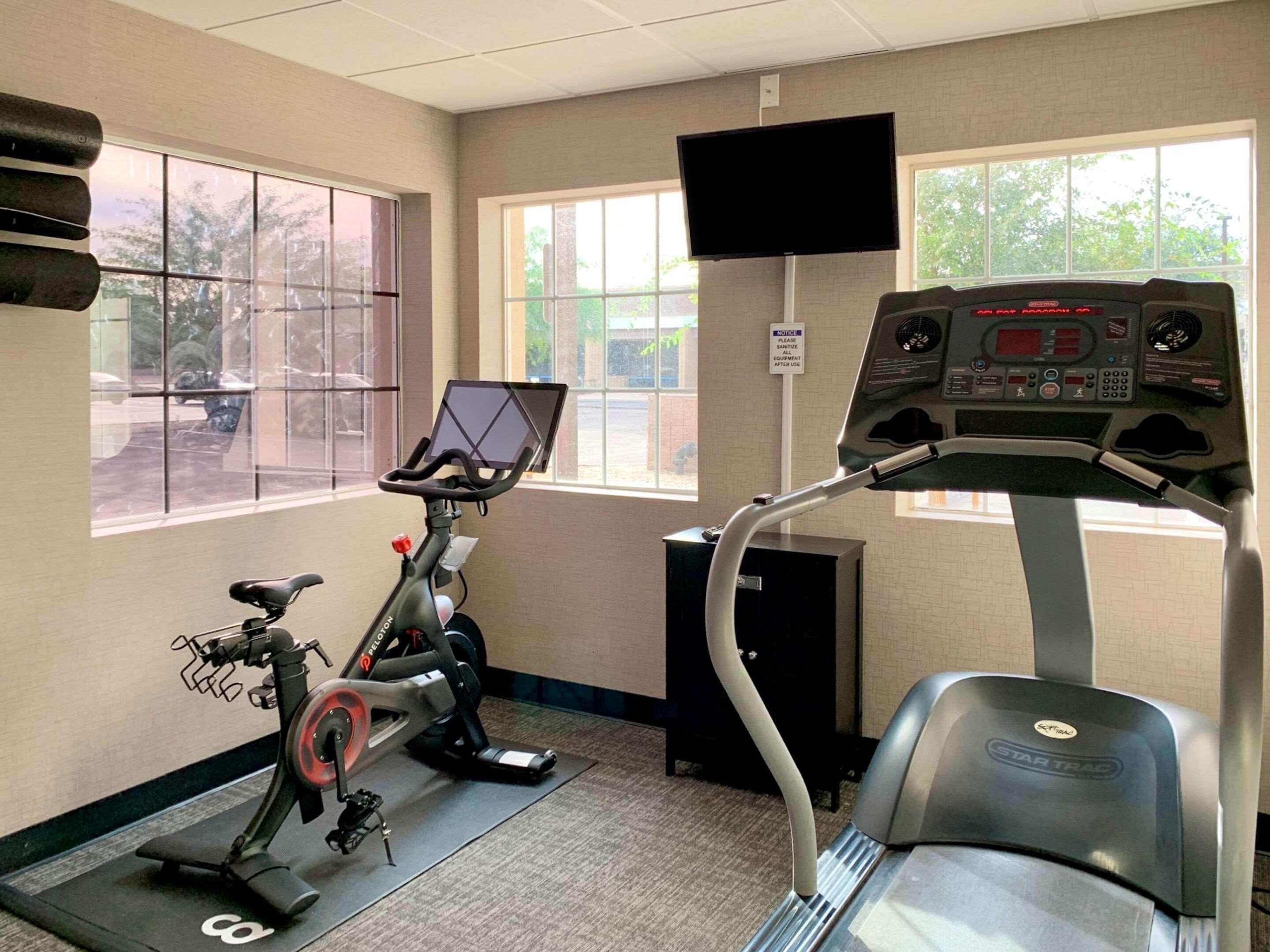 Un gimnasio con equipamiento de cardio, cinta de correr y elíptica.