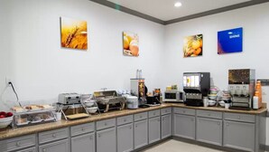 A breakfast bar with various food items, a coffee machine, and a microwave. - Comfort Inn & Suites Schulenburg TX (Schulenburg)