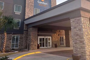 A hotel entrance with stone pillars, a sign for Comfort Suites, and a palm tree. - Comfort Suites Seabrook Kemah (Seabrook)