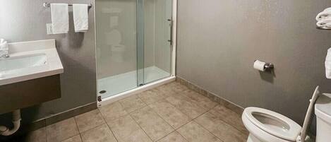 A bathroom with a glass shower enclosure, a toilet, a sink, and a towel rack.