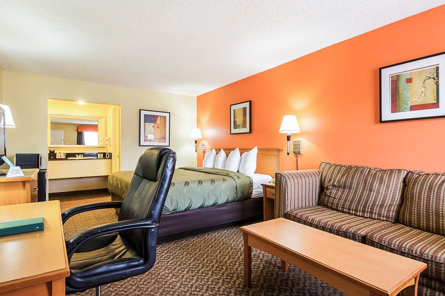 A hotel room with a bed, a sofa, a desk, and a chair.