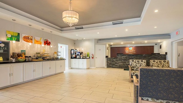 Un hall d’hôtel spacieux comprenant un comptoir d’accueil, un lustre, un coin cuisine et des espaces aménagés pour s’asseoir.