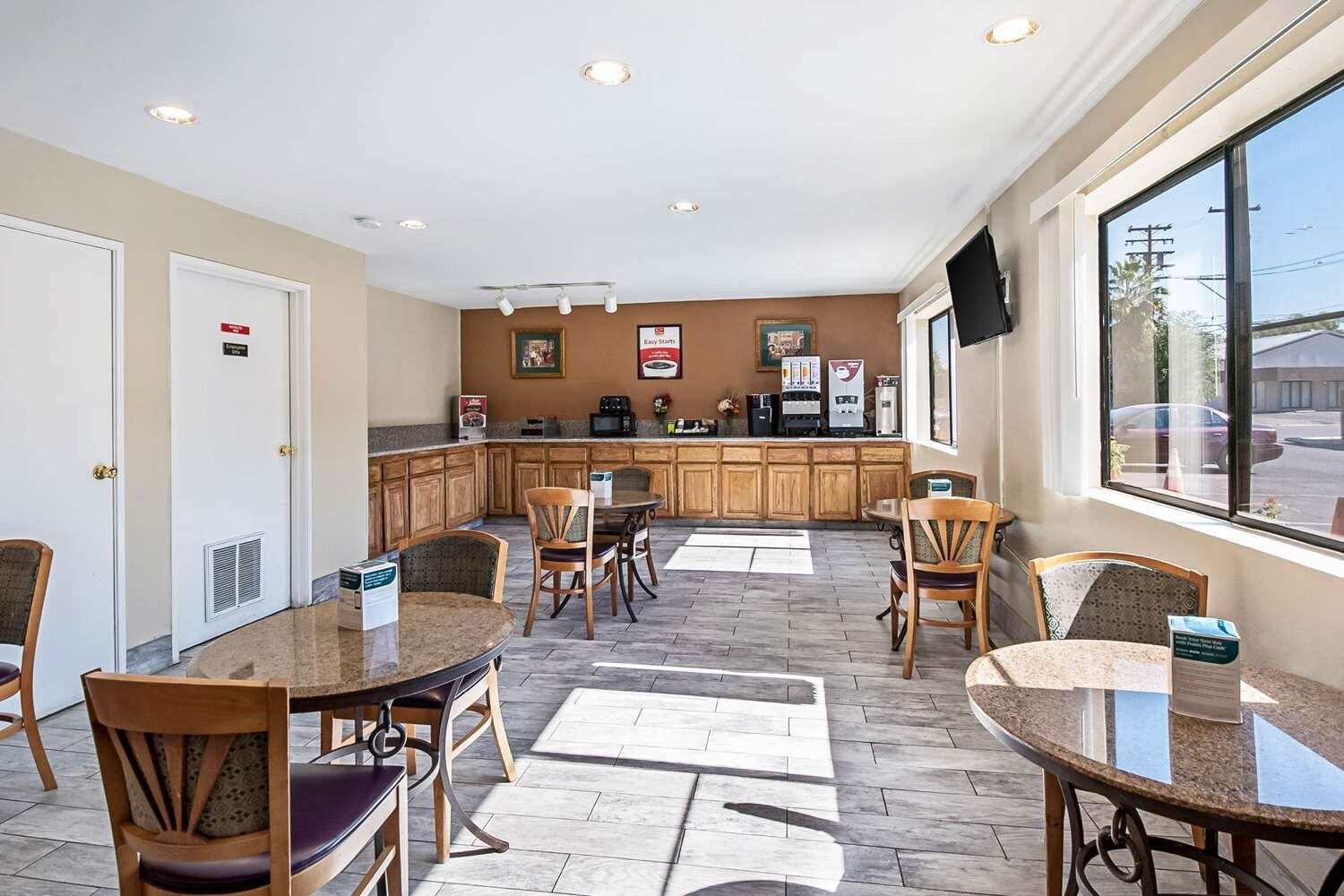 A hotel room with a dining area, kitchenette, and a large window with a view.