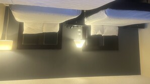 Une chambre d’hôtel avec un lit, une table de chevet et une lampe fixée au mur.