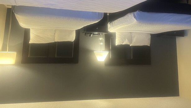 Un plafond avec un luminaire et un lit avec une literie blanche.