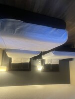 A ceiling with a light fixture and a bed with white bedding.