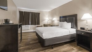 Habitación de hotel con cama, mesitas de noche, lámparas, un televisor de pantalla plana, escritorio con ordenador y ventana con cortinas.