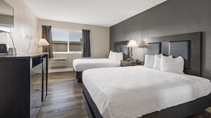 Une chambre d’hôtel avec deux lits, un bureau et une fenêtre avec des rideaux.