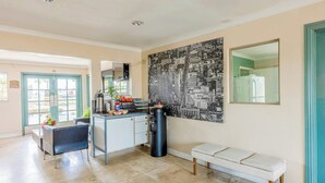 A modern kitchen with a coffee machine, a bench, and a large cityscape mural. - Hotel Avenida - Oceanside Camp Pendleton (Oceanside)
