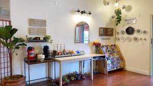 Et køkken med kaffestation, et spejl, en opslagstavle og en samling antikke tallerkener.