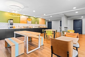 Um lobby de hotel moderno com um balcão de café, área de estar e mesa de recepção.