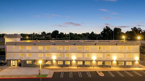 A multi-story hotel with a row of rooms, a parking lot, and street lamps. - Spark by Hilton Modesto (Modesto)