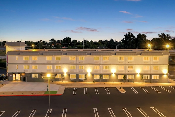 A multi-story hotel with a row of rooms, a parking lot, and street lamps. - Spark by Hilton Modesto (Modesto)