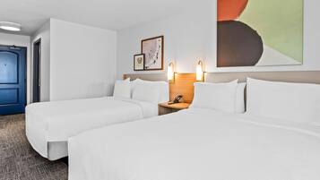 A hotel room with two beds, a wooden headboard, a wall-mounted phone, and a door.