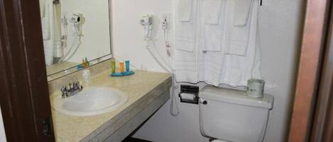 A bathroom with a sink, mirror, hairdryer, and towel rack.