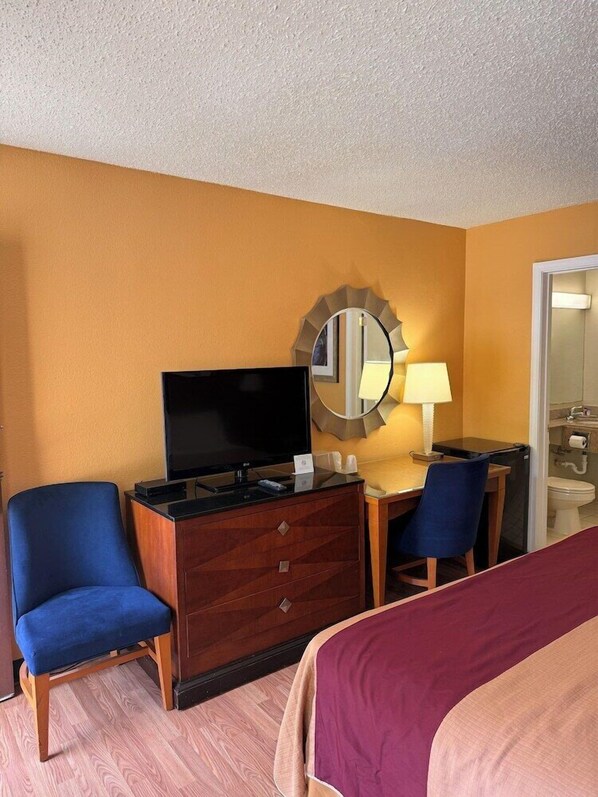 A hotel room with a bed, a TV, a desk with a lamp, and a mirror. - Executive Inn Schenectady (Schenectady)