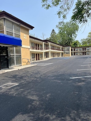 Un motel con un parcheggio, edifici a più piani e un tendone blu sopra l'ingresso.
