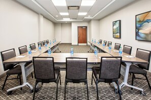 A conference room with a long table, chairs, water bottles, and a door in the background. - Candlewood Suites Cincinnati Northeast - Mason (Mason)