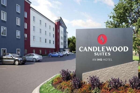 A hotel sign for Candlewood Suites at IHG Hotel, with a modern building in the background and several cars parked in the lot. - Candlewood Suites Cincinnati Northeast - Mason (Mason)