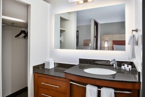A modern bathroom with a large mirror, two sinks, a vanity with drawers, and a towel rack. - Candlewood Suites Cincinnati Northeast - Mason (Mason)
