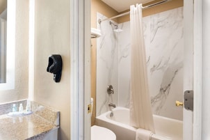 Un baño con pared de ducha de mármol, una bañera y un inodoro.