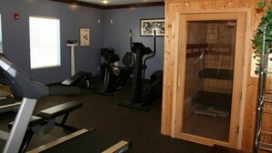 Une salle de sport équipée de matériel d’exercice, un sauna et une fenêtre avec des stores.