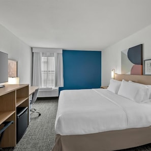 Ein Hotelzimmer mit Bett, Schreibtisch, Stuhl und Fernseher.