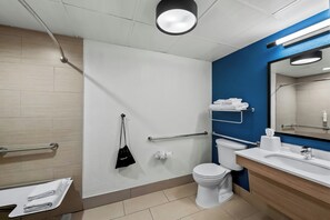 A modern bathroom with a white toilet, a sink with a mirror, and a towel rack. - Spark by Hilton Spring Lake Fayetteville (Spring Lake)