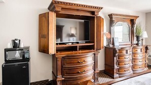 A hotel room with a wooden entertainment center, a small refrigerator, a microwave, and a large mirror. - Loge St. George (St. George)