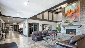 A spacious living area with leather sofas, a glass coffee table, and a fireplace. - Loge St. George (St. George)