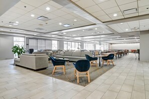 A spacious indoor area with a large sofa, chairs, and a dining area. - Holiday Inn Piscataway - Somerset (Piscataway)