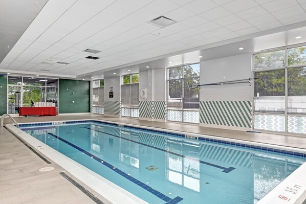 An indoor swimming pool with clear water, tiled walls, and a red table.