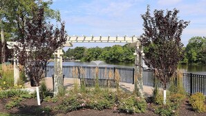 Un jardín con un pérgola, un cuerpo de agua y un puente.
