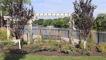 Un jardín con un pérgola, un cuerpo de agua y un puente.